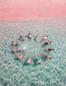 Двенадцать человек держатся за руки, лежат на воде на спине и образовали круг